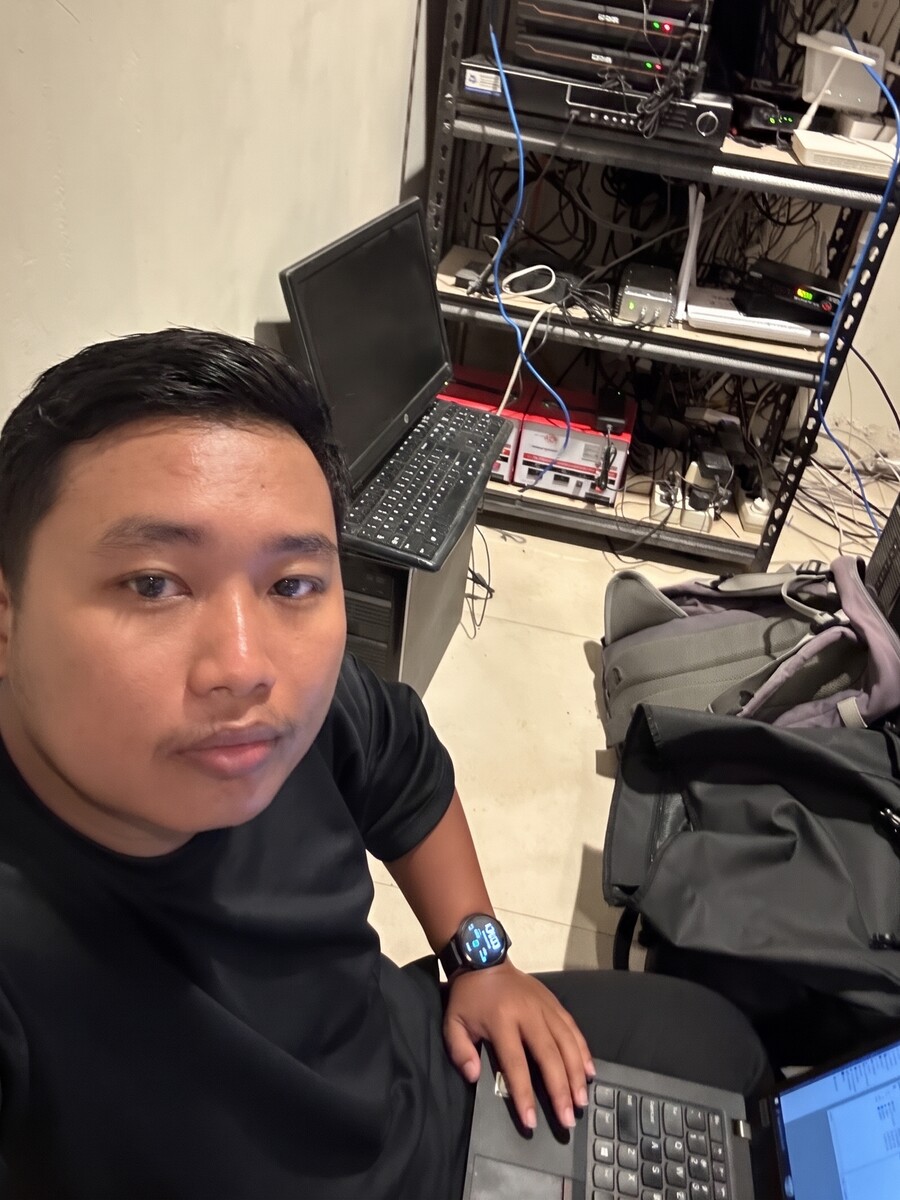 Nurhadianto sedang bekerja dengan laptop di depan rack perangkat jaringan